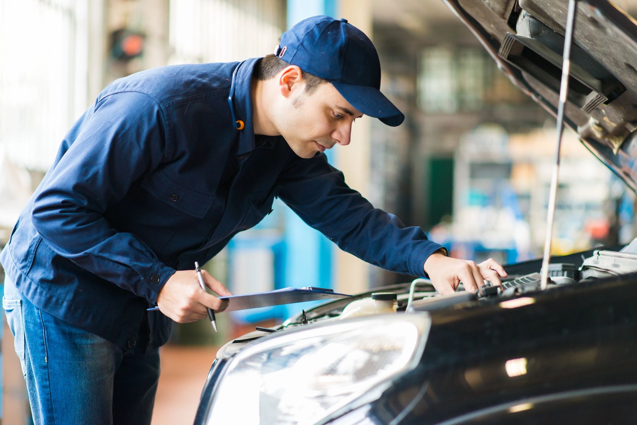 A man working on the hood of his car.